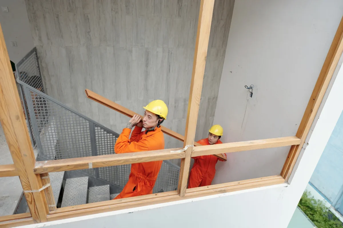 Builders carrying timber indoors representing the about us team at Deck Builders Taupo dedicated to each project.